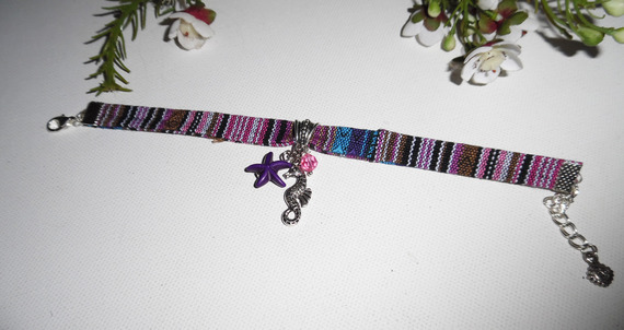 Bracciale in tessuto colorato con nappe a forma di cavalluccio marino e stella marina viola