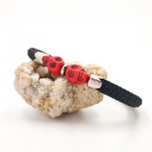 Bracciale con doppio teschio e ossa incrociate con pietre rosse su una spessa corda nera